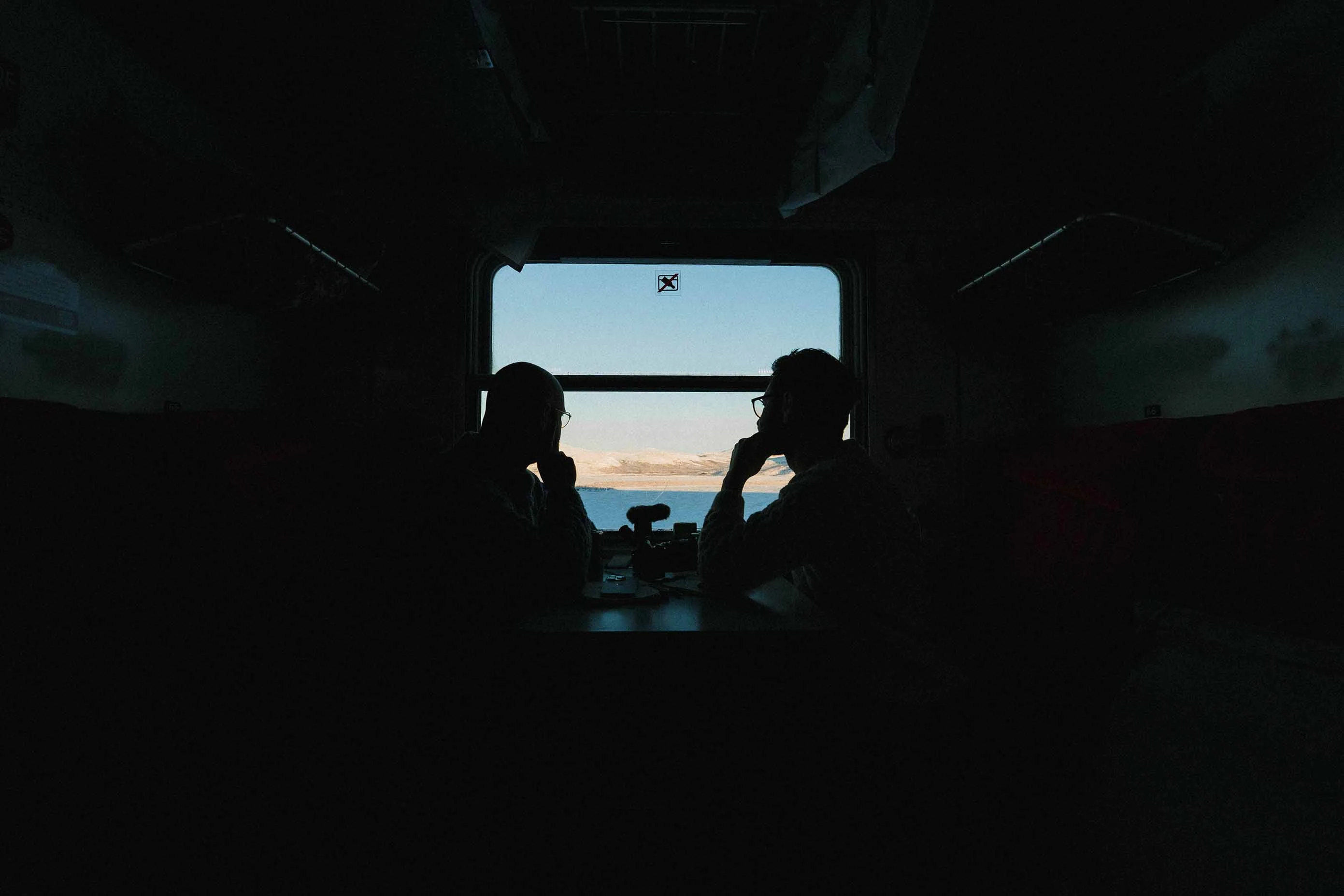 2 mens watching in the window of a train