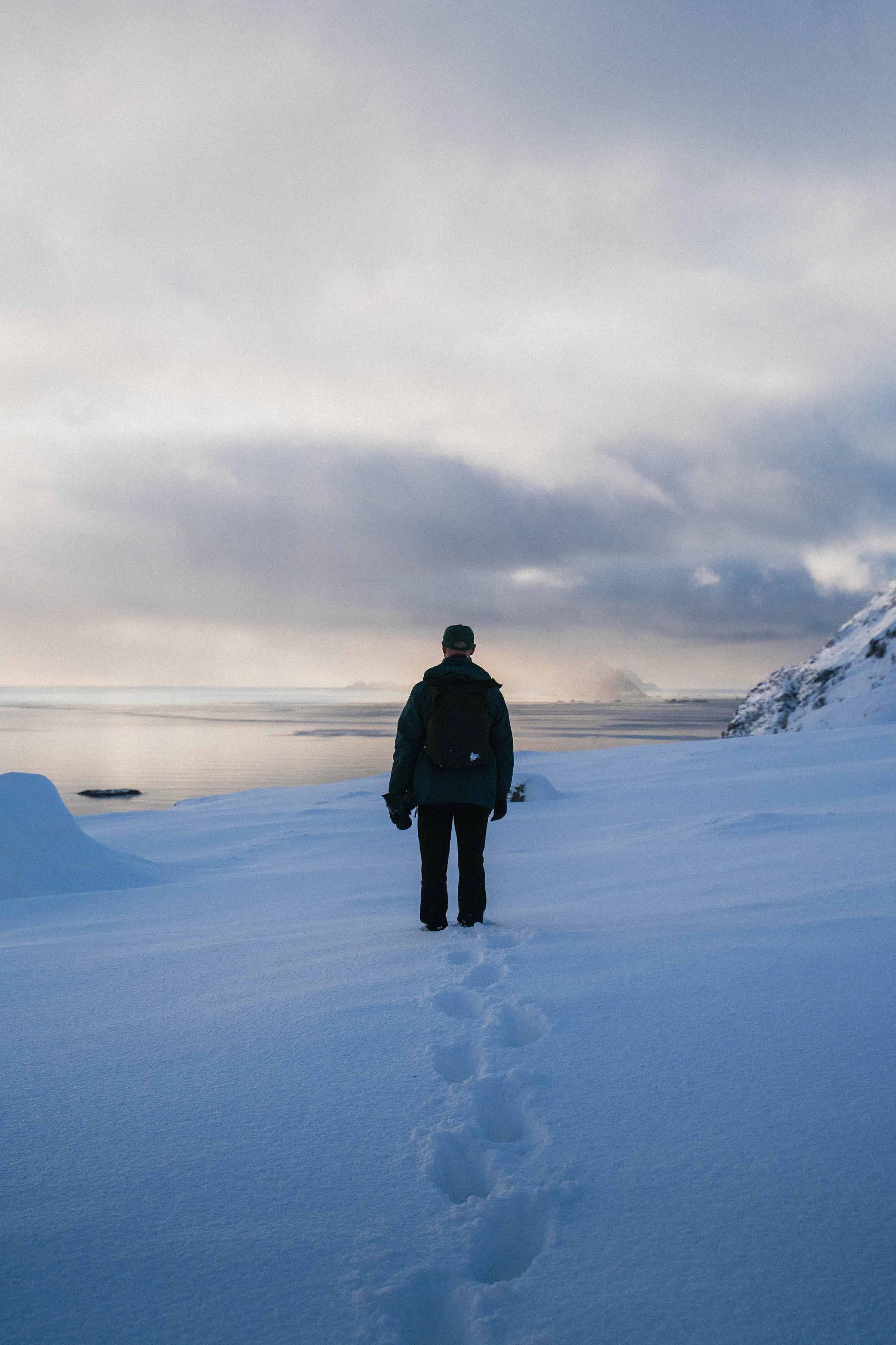 Men in the snow on top of the mountain watching the sea